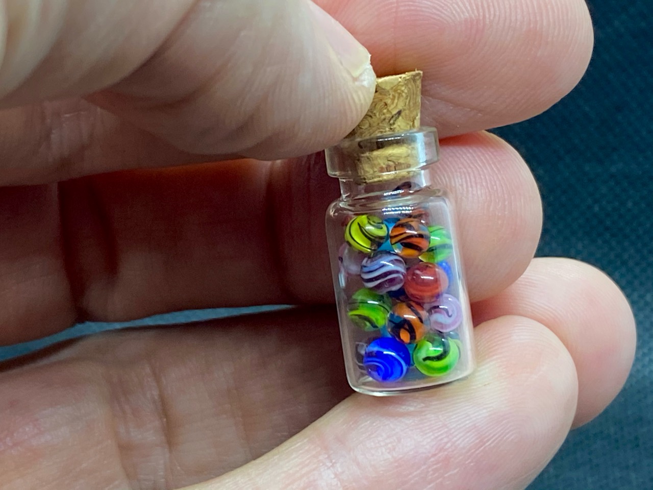 Rainbow Swirl Mini Micro Marbles: Alternate hand-held bottle view showing the micro marbles for scale