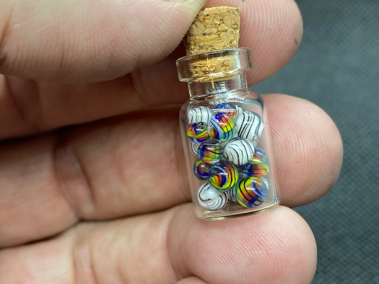 Rainbows & White Tigers Mini Micro Marbles: Hand-held miniature bottle showing the tiny scale of the rainbows and White Tigers