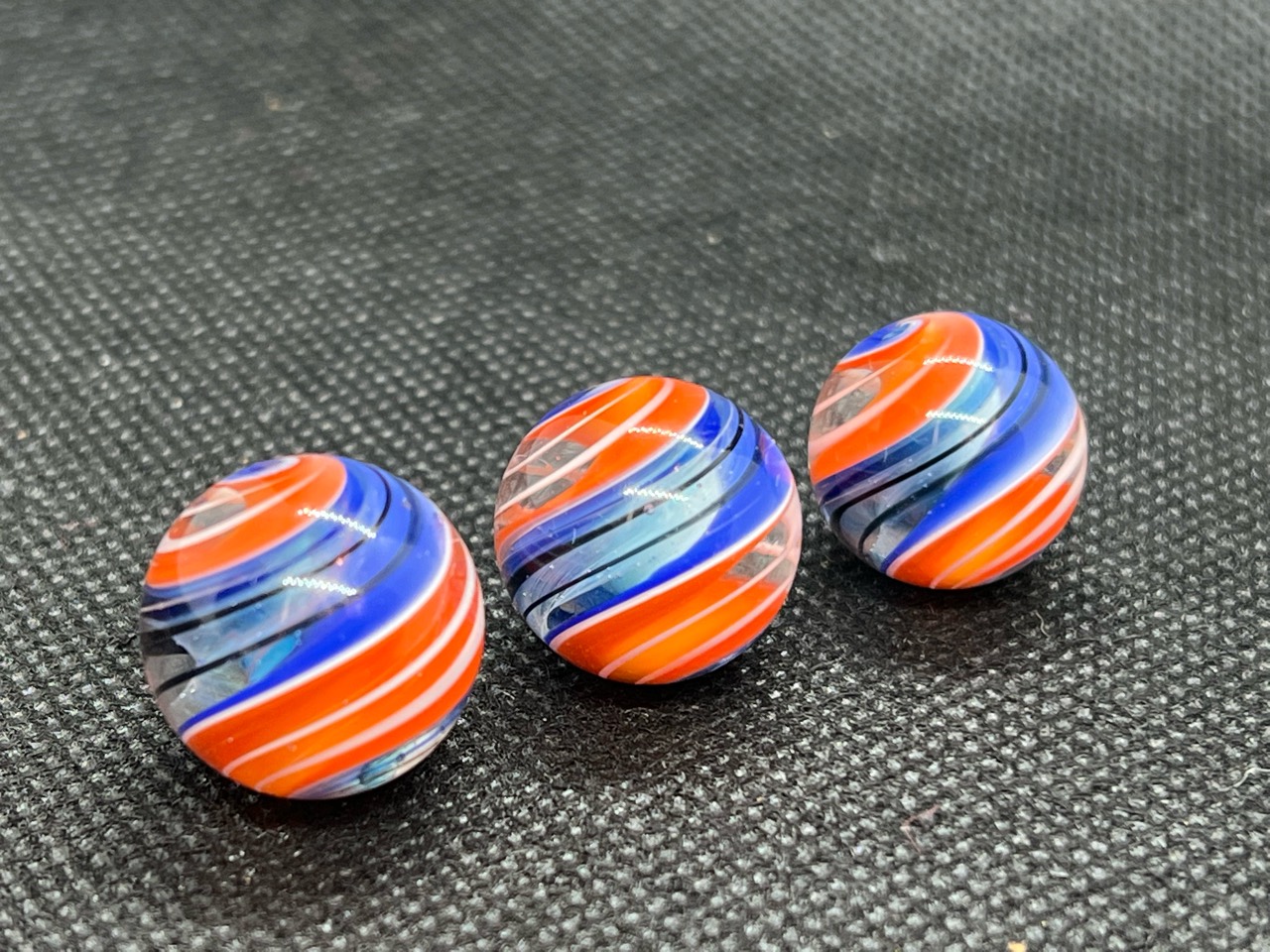 Tangerine Orange & Sky Blue Pee-wee Set: Three Pee-wee marbles with tangerine-orange and blue ribbons traced by fine white and black lines