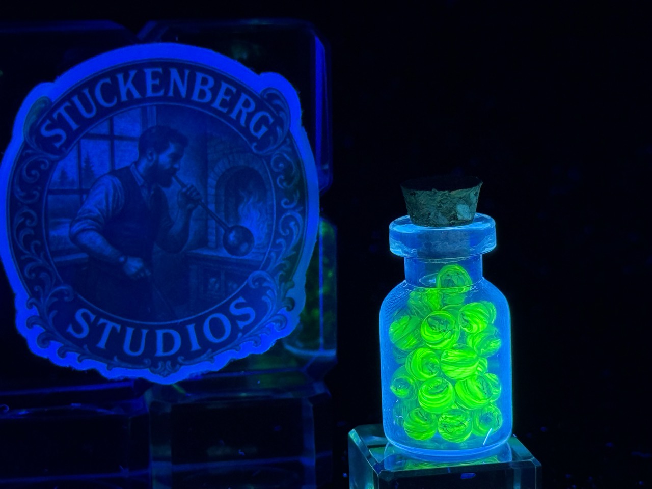 UV Champagne Mini Micro Marbles glowing brilliant green in their jar under UV light