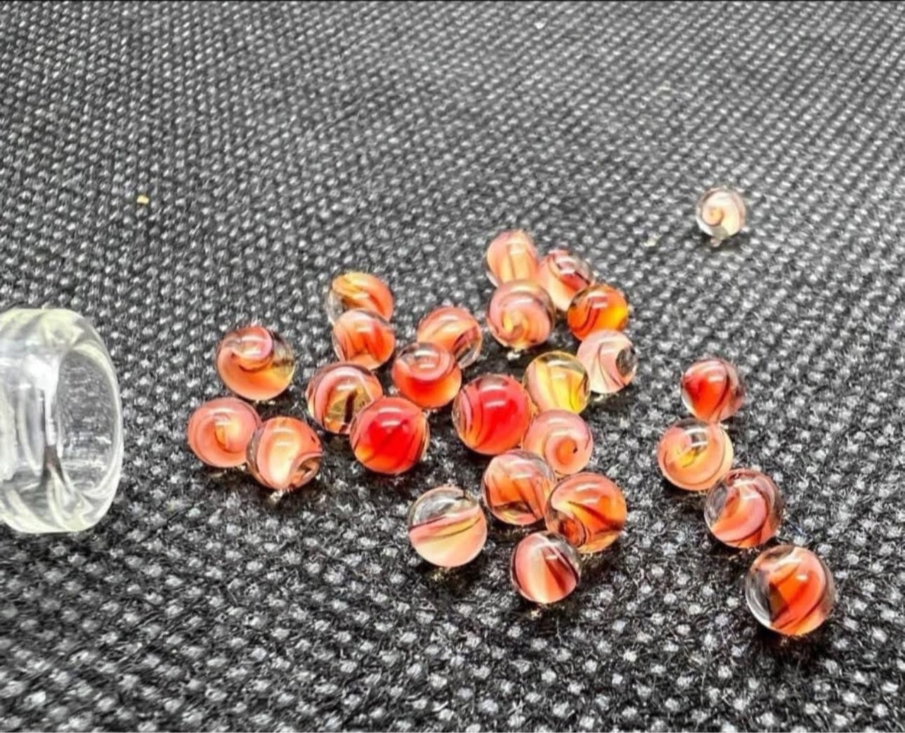 UV Peaches & Cream Micro Marbles: Peach, cream, and orange micro marbles scattered beside an open glass vial in ordinary light